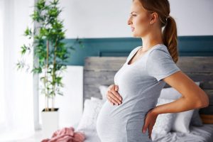 Беременная держится за живот и поясницу